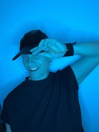 a woman in a black hat posing in front of a blue wall