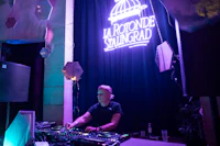 a dj in front of a large neon sign
