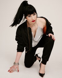 a woman crouching down in front of a white background